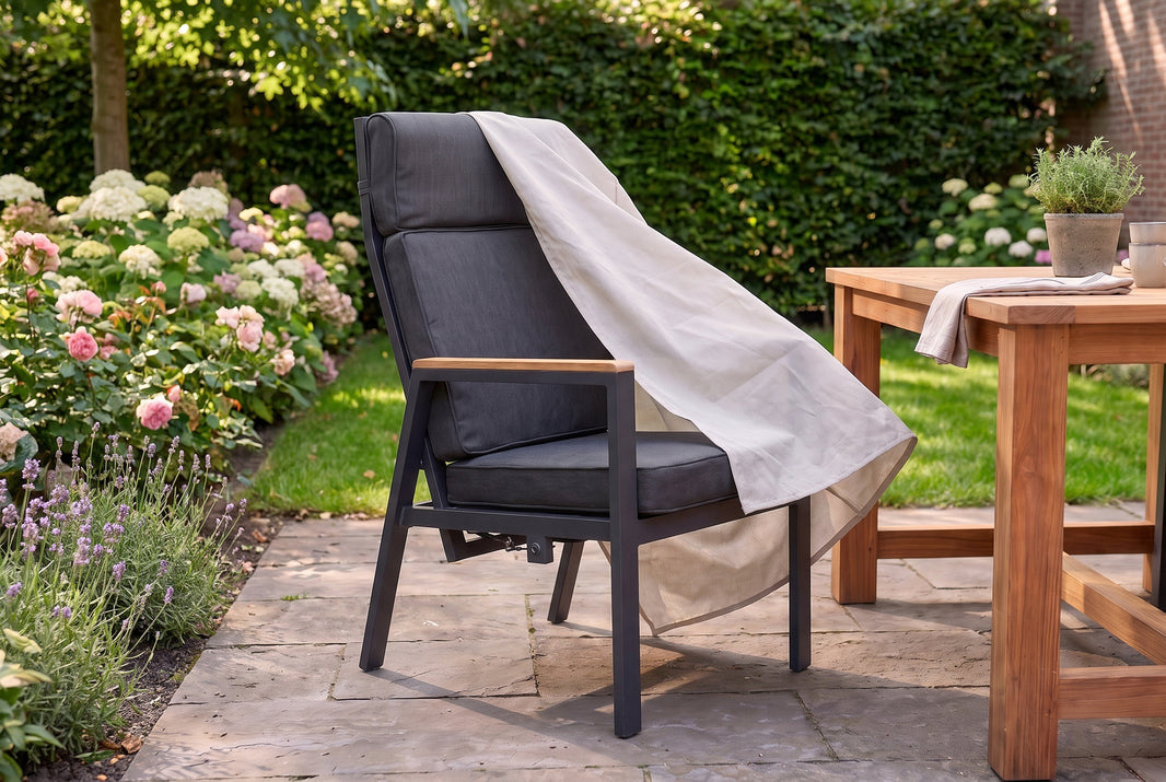 Teakhouten tuinstoelen op een terras met een beschermhoes half over één stoel gedrapeerd