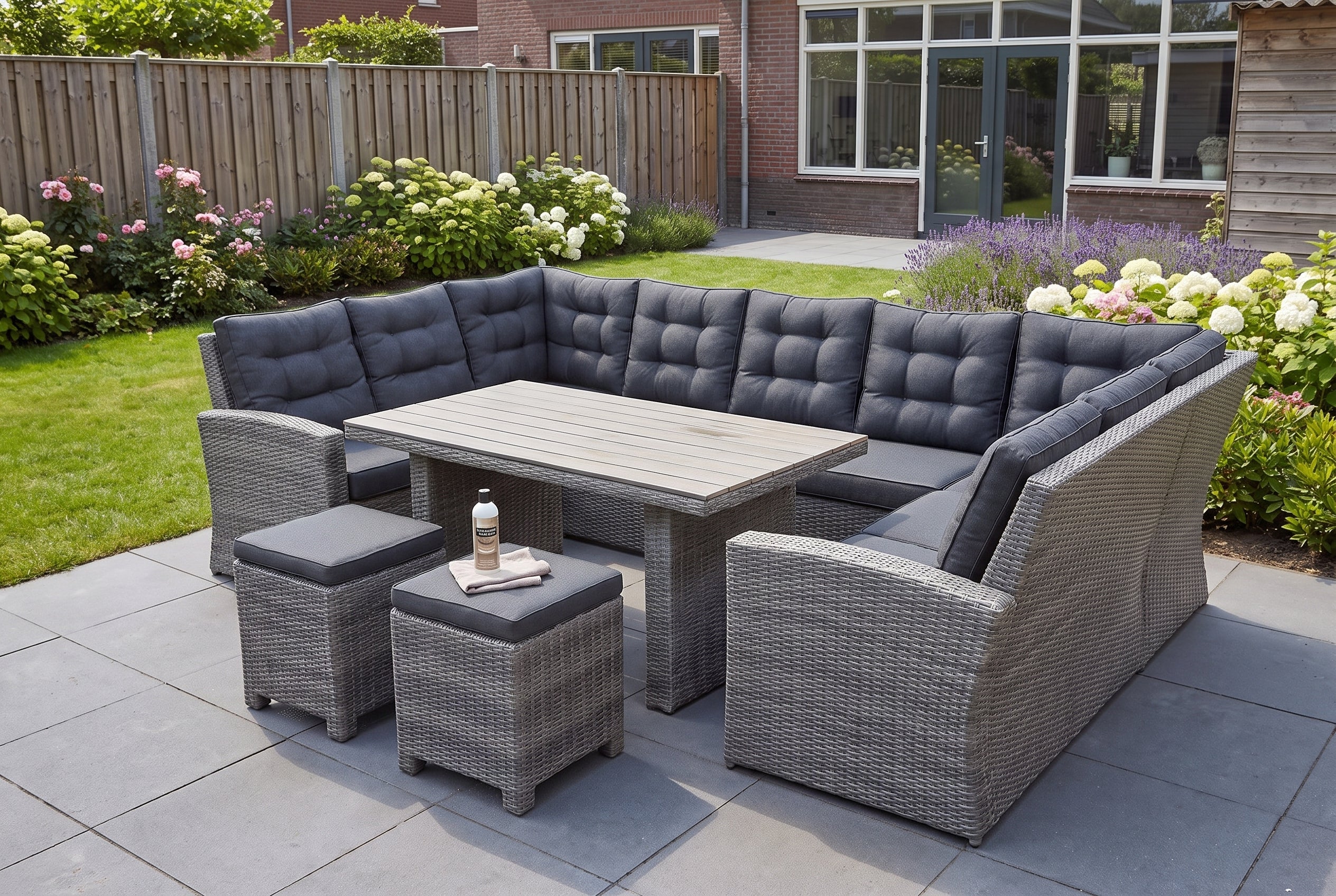 Kunststof tuinset op een terras met een lichte verweringsvlek op het tafelblad en schoonmaakspullen op een stoel