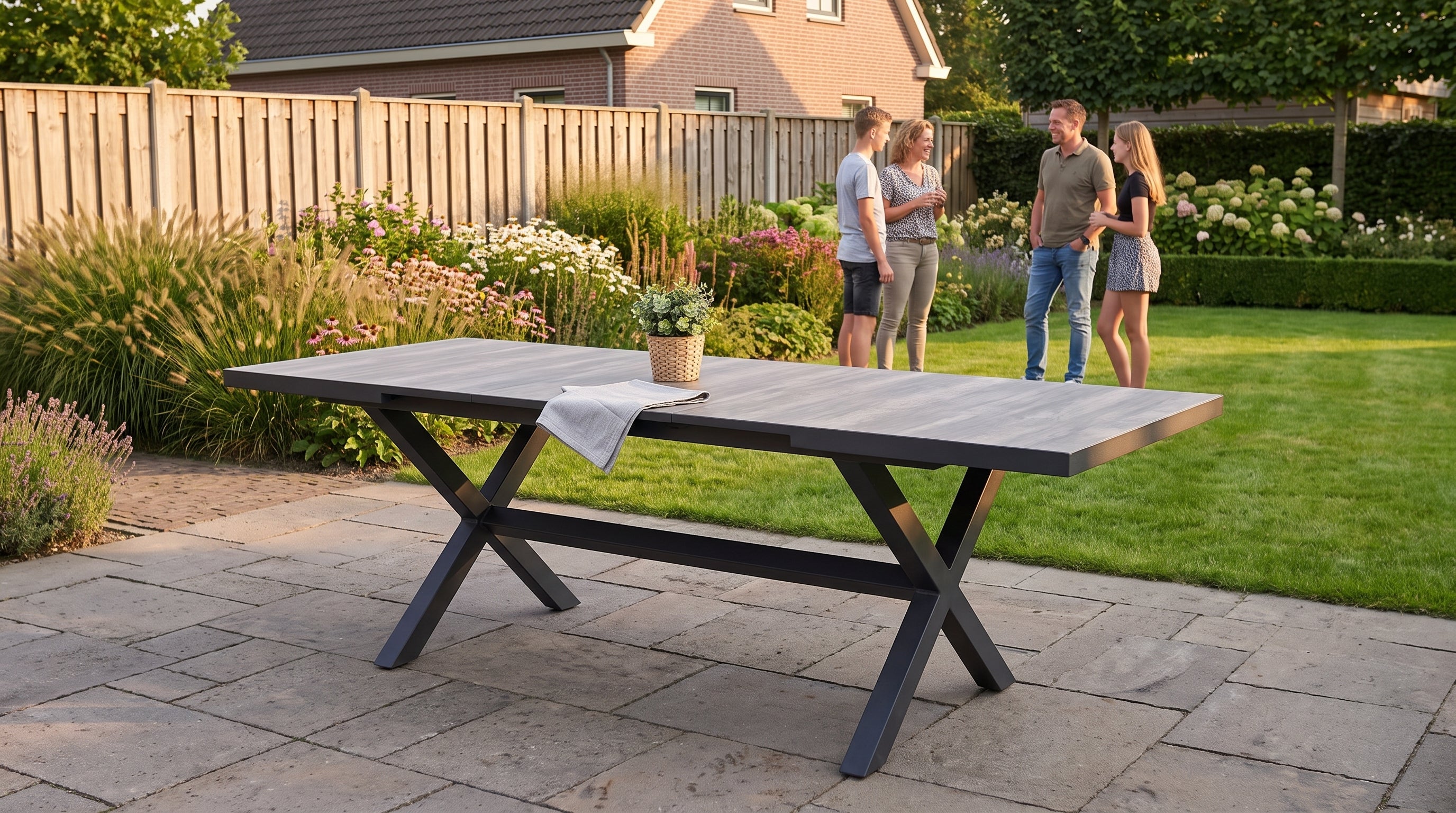 Uitschuifbare tuintafel halverwege uitgetrokken op een terras tijdens golden hour, gezin net klaar met eten